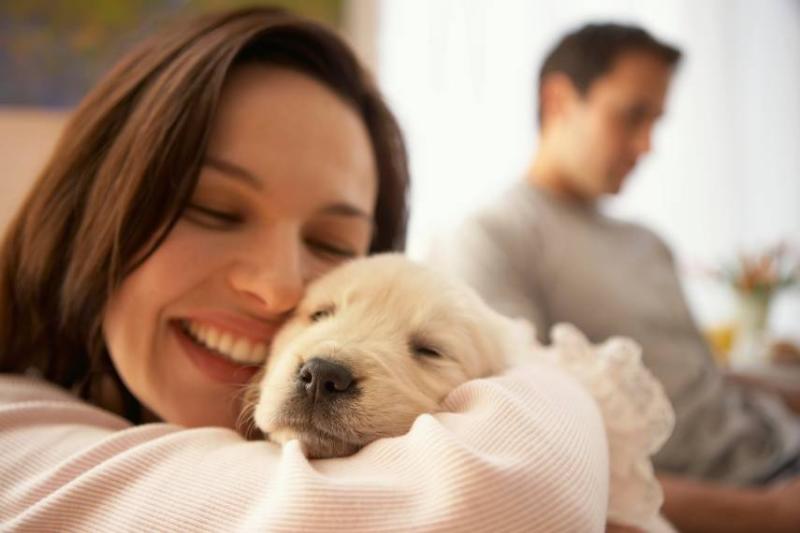 A happy woman holding a puppy.