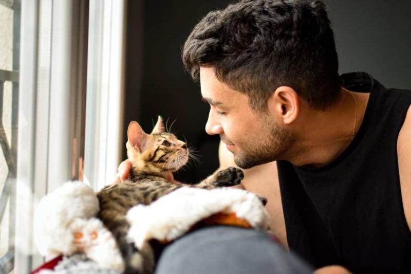 Image of a man looking at his kitten. 
