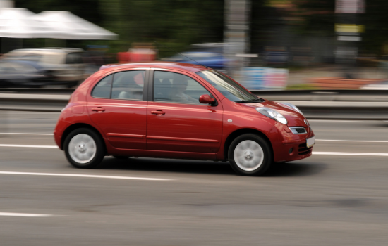 red nissan micra driving on road