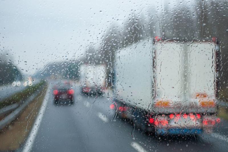 View through a rainy windshield of a lorry driving on a road